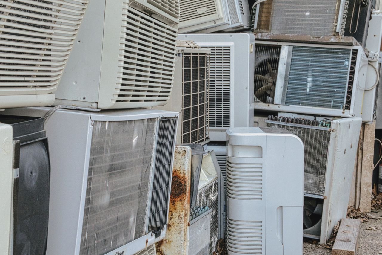 about-01 A collection of various old and broken air conditioning units piled outdoors.