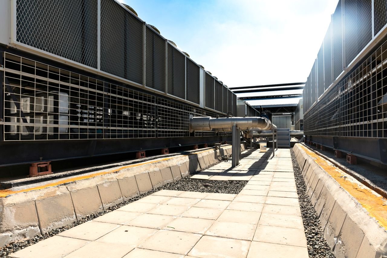 our-services-1 View of a large industrial cooling system with metal pipes and grids outdoors under bright daylight.